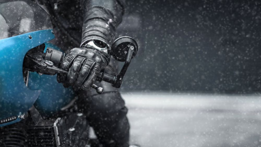 December motorcycle safety NJ with rider using gloves and helmet face shield in falling snow during winter riding conditions