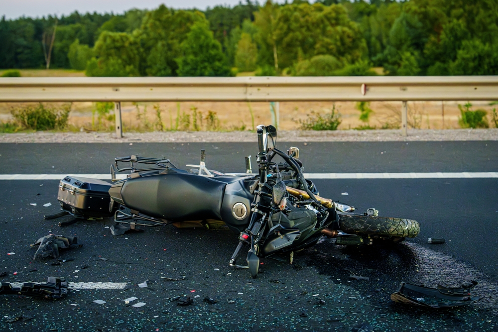 Damaged motorcycle lying on highway after crash during motorcycle injury claims investigation