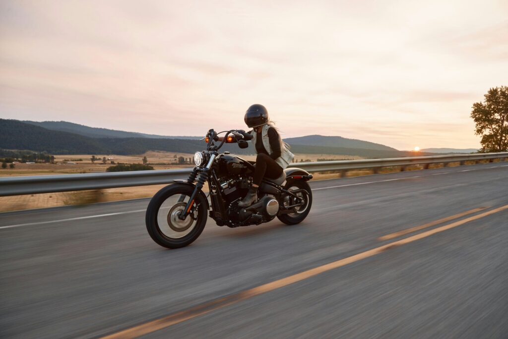 Motorcyclist riding on an open highway at sunset wearing protective gear