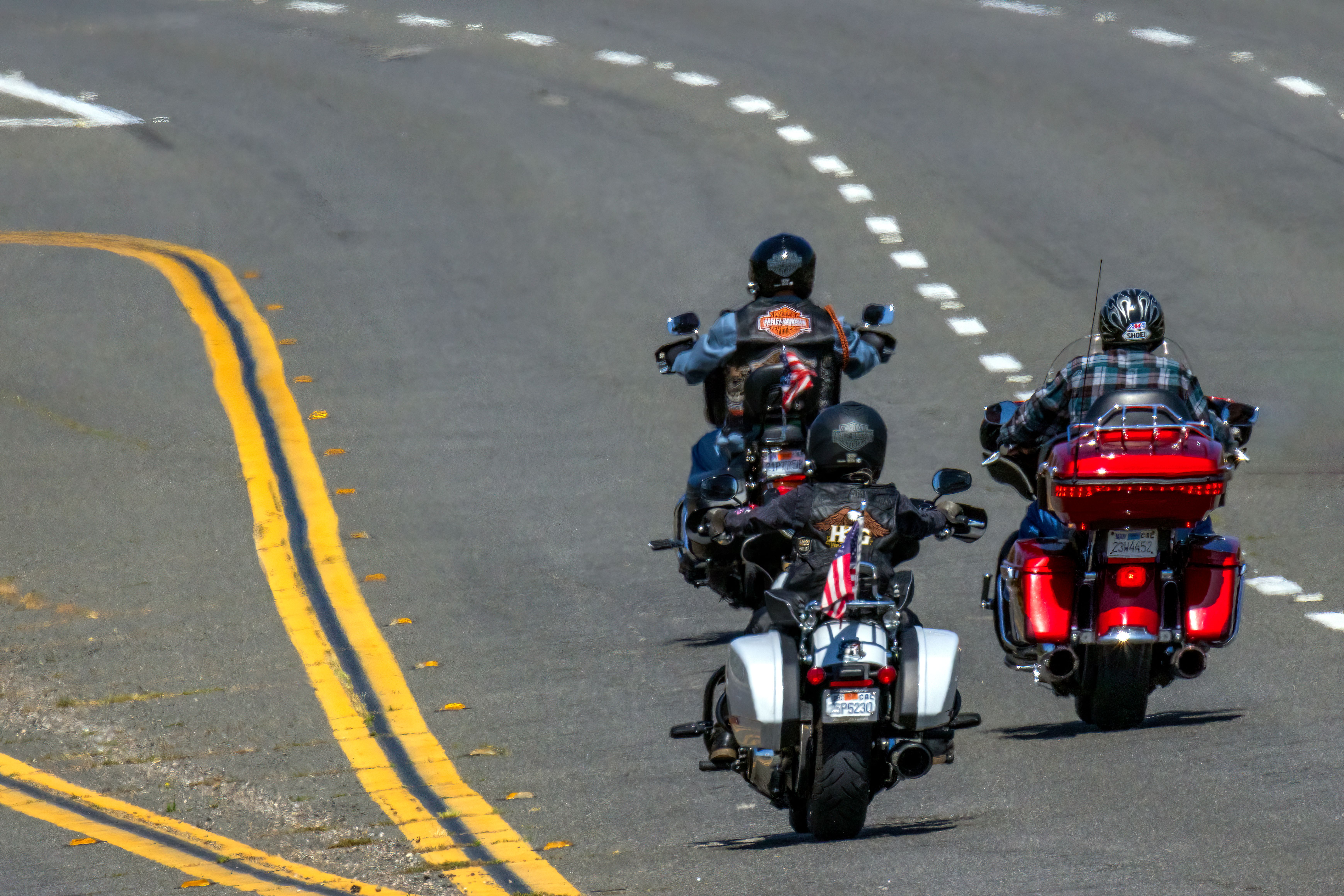 Three motorcyclists riding Harley-Davidson touring bikes down a highway