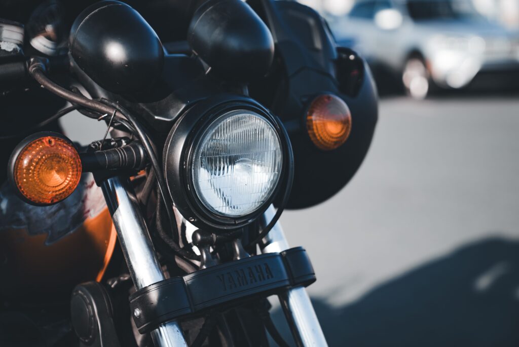 Close-up of the headlight and turn signals on a black motorcycle parked on a New Jersey street