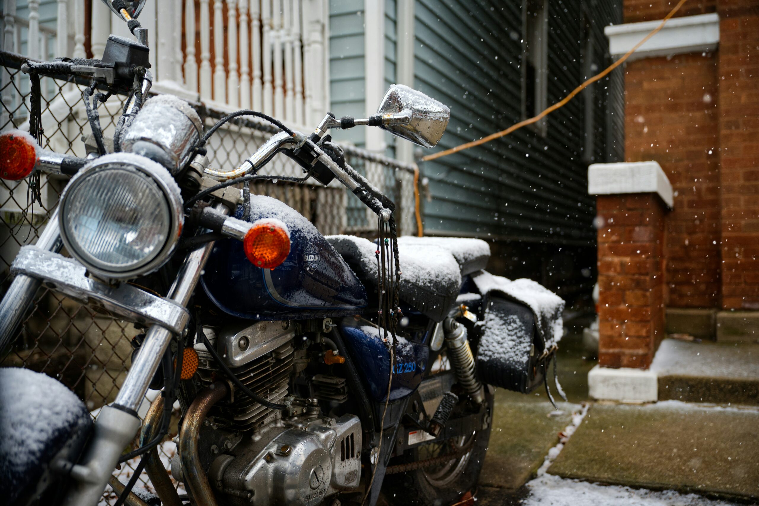 Snow-covered motorcycle parked beside a fence, a reminder to protect your NJ motorcycle accident claim before winter storage.